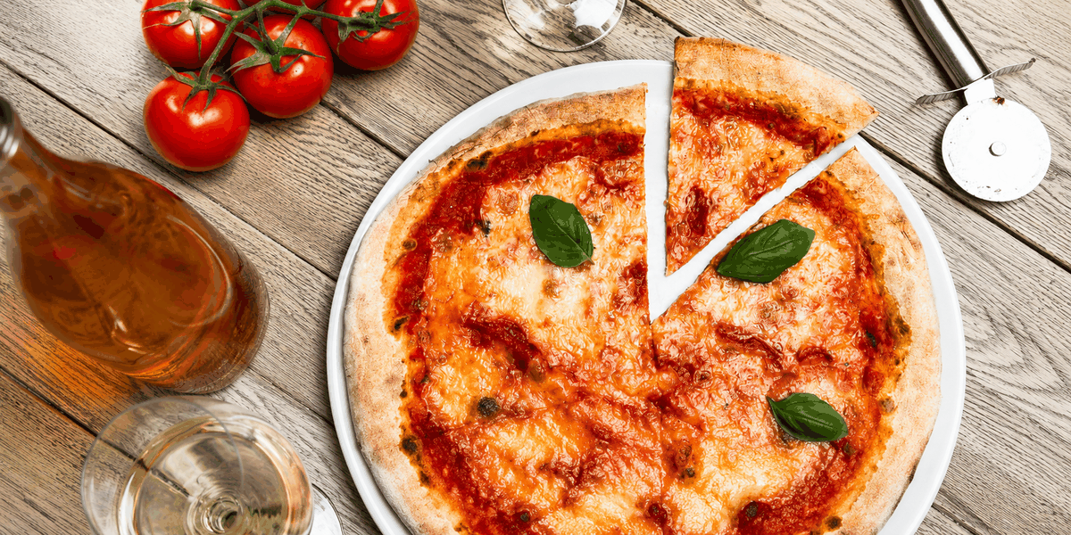 Verse margherita van bovenaf, met trostomaten en een glas wijn ernaast