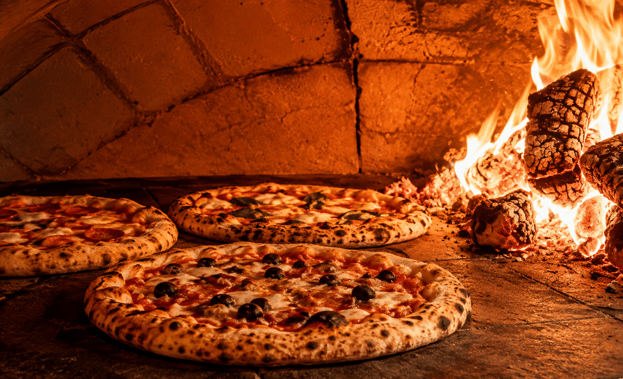 Drie pizza’s bakken op de steenvloer naast het houtvuur in de oven